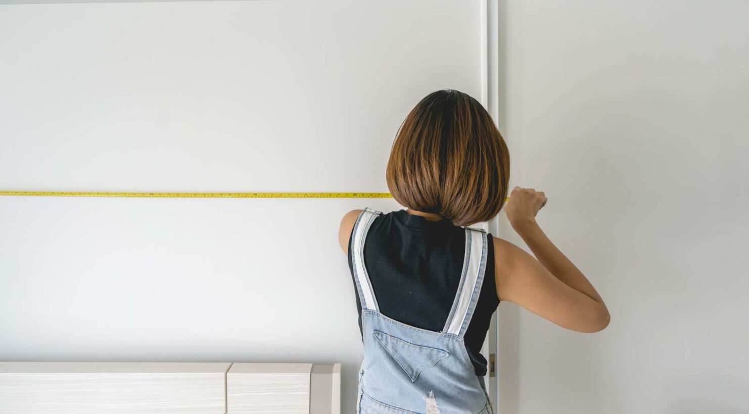 Woman measuring wall